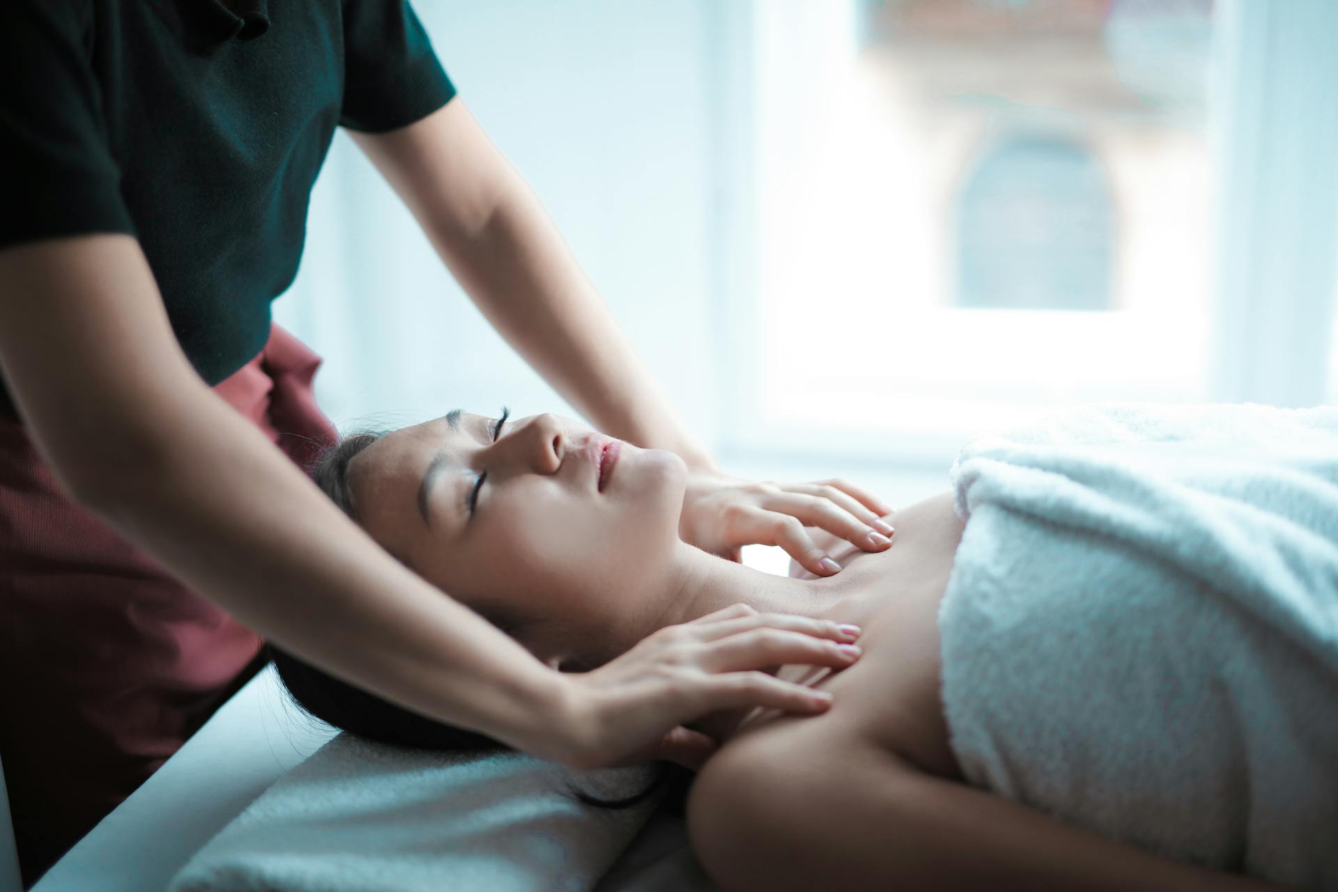 The masseuse is massaging the client's shoulders.