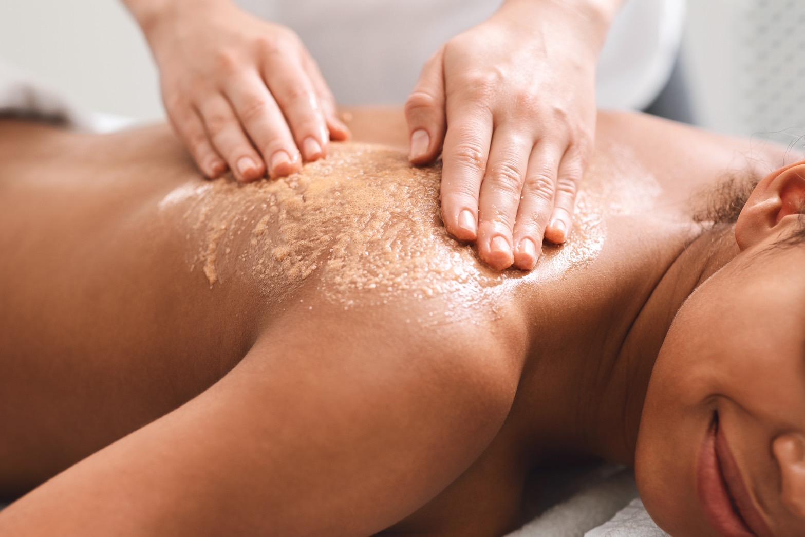 The therapist is performing a body scrub massage on the client's back.