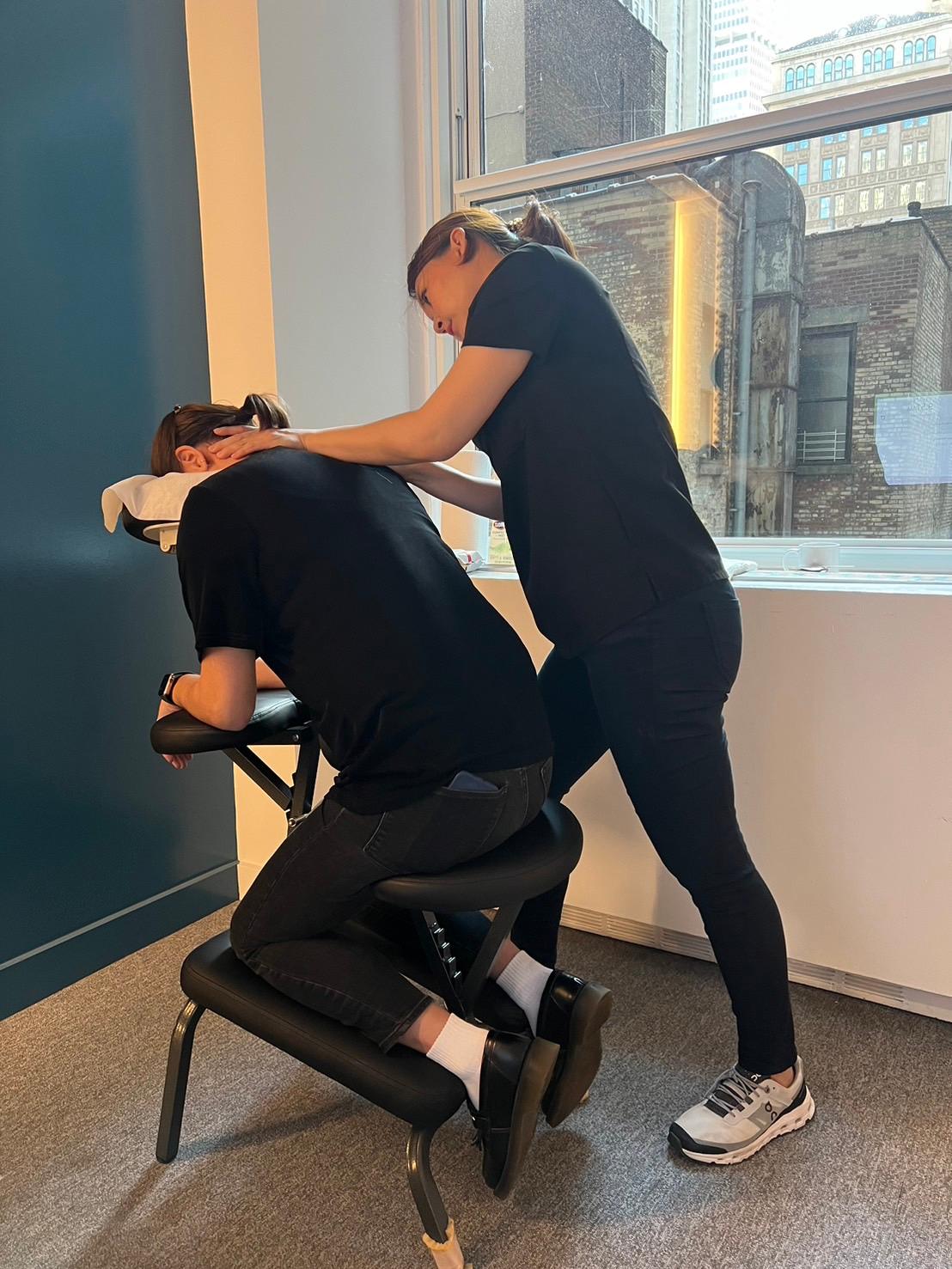 The masseuse is performing the chair massage for the client.